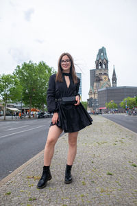 Full length portrait of young woman standing in city