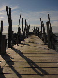 Wooden posts on beach against sky during sunset
