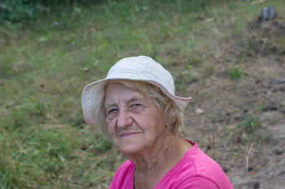 Portrait of senior woman wearing hat on grassy field