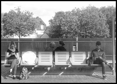 People sitting on seat against buildings