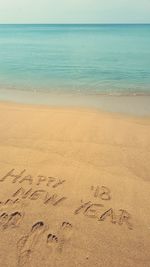 Text on sand at beach against sky