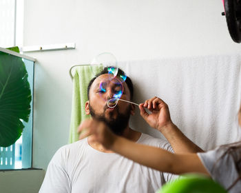 Father blowing bubbles with daughter at home