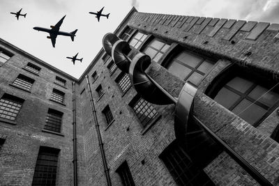 Low angle view of airplane flying over building against sky