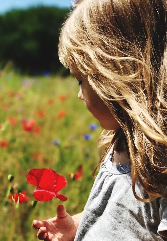 CLOSE-UP OF A GIRL WITH FLOWERS IN THE BACKGROUND