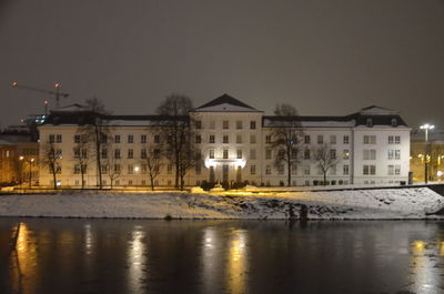 Buildings by river against sky at night