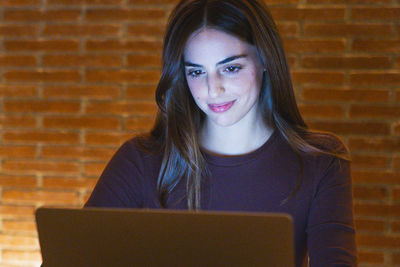 Portrait of young woman using laptop at home