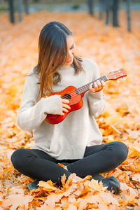 Side view of young woman holding autumn leaves