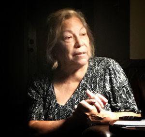 Portrait of woman sitting against black background