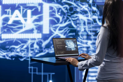 Midsection of woman using laptop at office