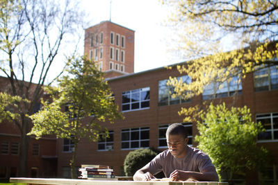 Man reading book while sitting at campus