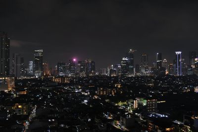 Illuminated cityscape against sky at night