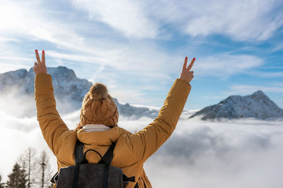 Rear view of female hiker with outstretched arms looking at amazing view of mountains