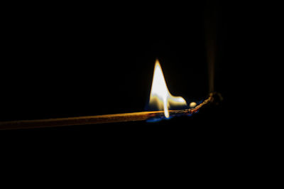 Close-up of lit candle in dark room