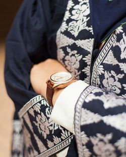 Midsection of woman wearing wristwatch standing with arms crossed