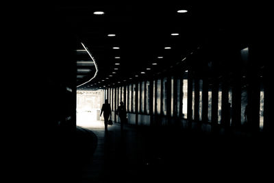 Silhouette man walking in illuminated tunnel