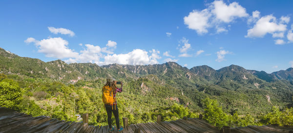 Rear view of woman walking on mountain against sky