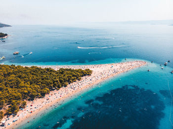 View over bol, croatia with drone capturing turquoise adriatic sea and beach life during the summer.