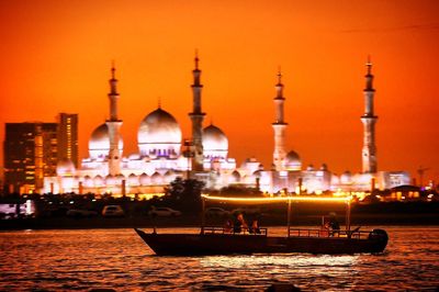 Boat moving on river in front of sheikh zayed mosque during sunset