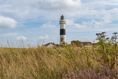 Lighthouse on field against sky