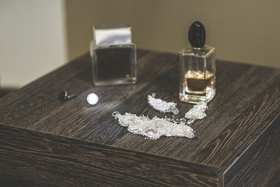 High angle view of jewelry with perfume spray on wooden table