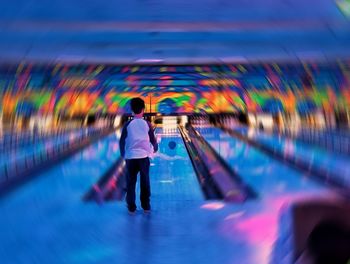 Blurred motion of man standing against illuminated lights at night