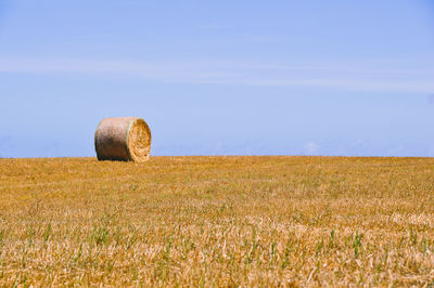 Hay bales on field against sky