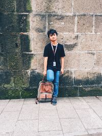 Full length portrait of teenage girl against wall