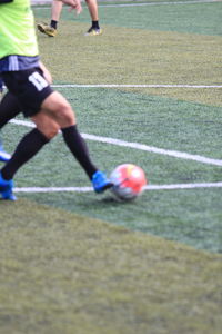 Low section of people playing soccer on field