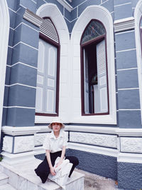 Portrait of woman sitting against building