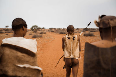 Rear view of people walking on sand