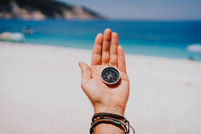 Midsection of person holding compass at beach