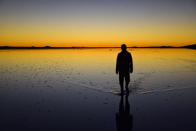 Silhouette man walking at salar de uyuni during sunset
