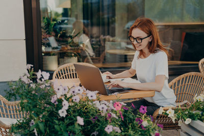 Young woman using mobile phone while sitting on table
