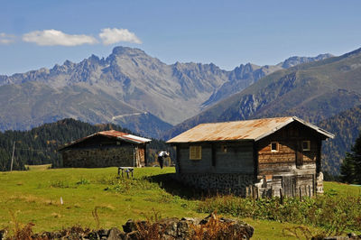 House on field by mountains against sky