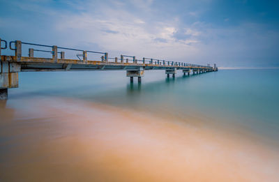 Pier over sea against sky during sunset