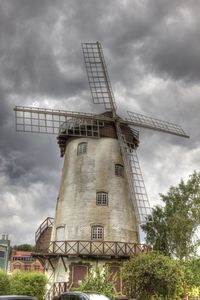 Low angle view of traditional windmill against cloudy sky