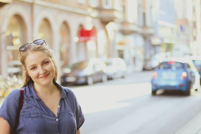 Smiling young woman standing on street in city