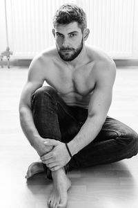 Portrait of shirtless man sitting on floor at home