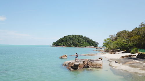 Couple kissing while standing on rock at beach against sky