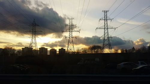 Low angle view of electricity pylon against cloudy sky