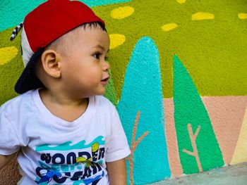 Low angle view of boy looking away against wall