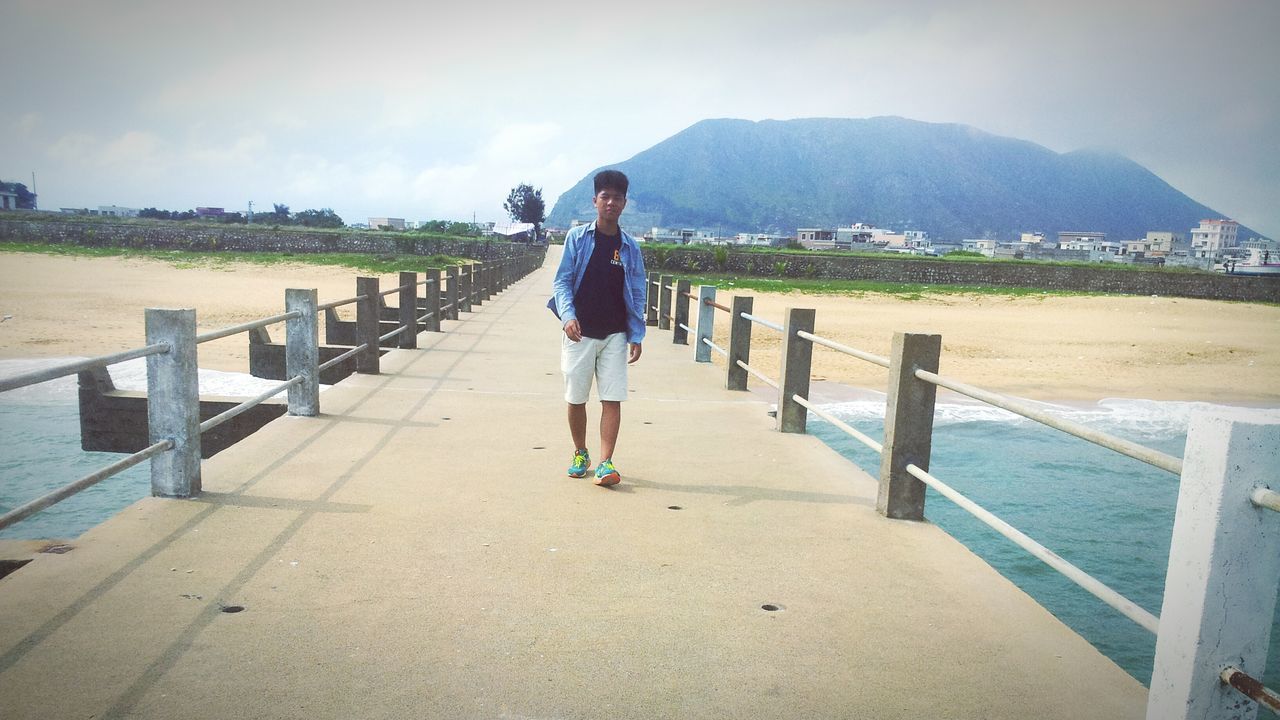 full length, rear view, leisure activity, lifestyles, sky, railing, walking, the way forward, casual clothing, water, sea, person, tranquil scene, nature, tranquility, men, beach, standing