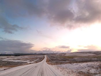 Road amidst empty land against sky during sunset