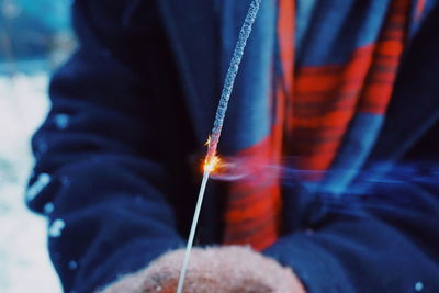 Midsection of woman holding lit sparkler