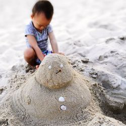 High angle view of boy playing with sand by castle at beach