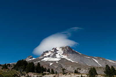 Low angle view of mount hood against blue sky and cloud formation 