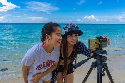 Young woman photographing at beach against sky