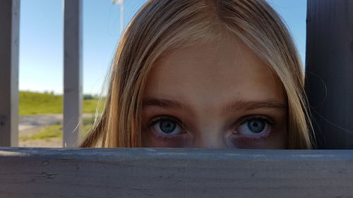 Close-up portrait of peeking through fence