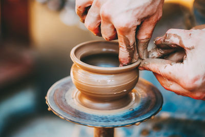 Cropped hands of person molding shape on pottery wheel