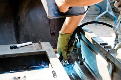 Cropped hand of male welder welding vehicle